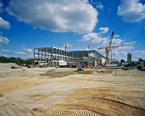 A steel-frame building under construction with tower cranes on site.